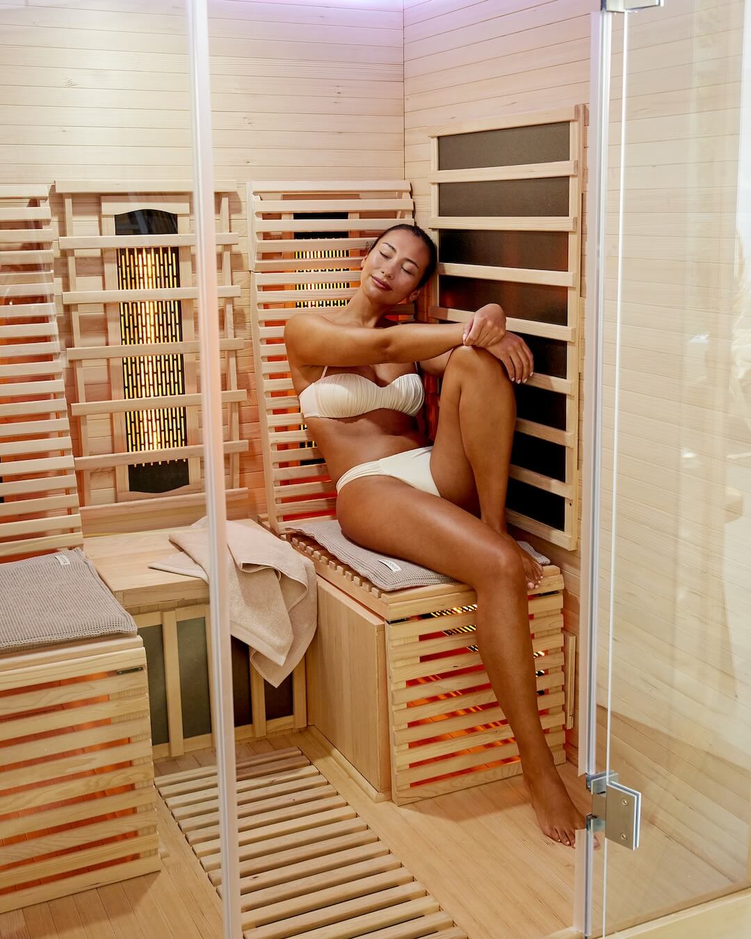 Frau sitzt auf einem Saunasitzkissen angelehnt in der Infrarotsauna.