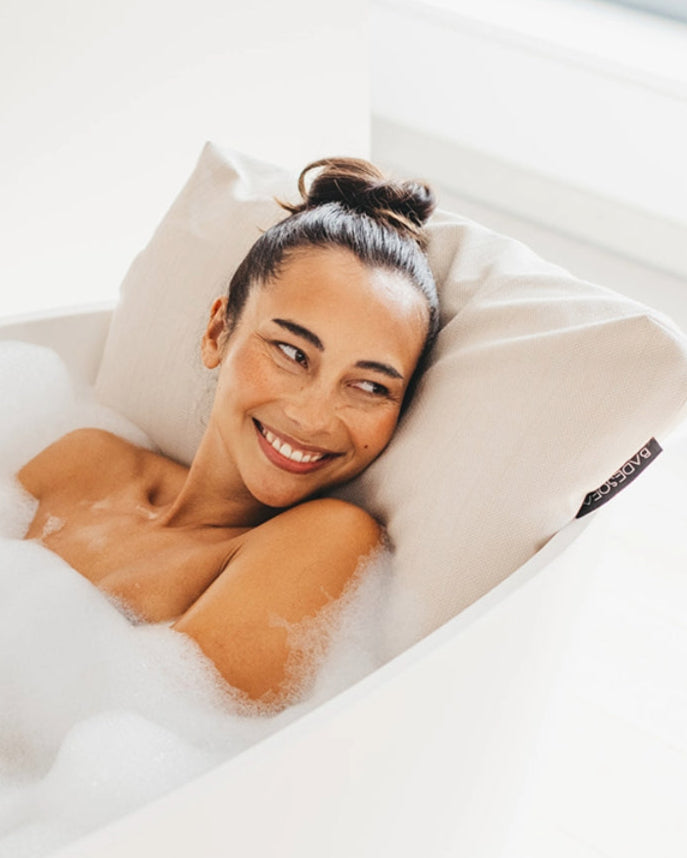 Perlmutt Badesofa Rückenkissen (Size Large) in einer freistehenden Badewanne, mit lächelnder Person, die sich entspannt anlehnt. $ Freistehende Badewanne | Size Large | Perlmutt