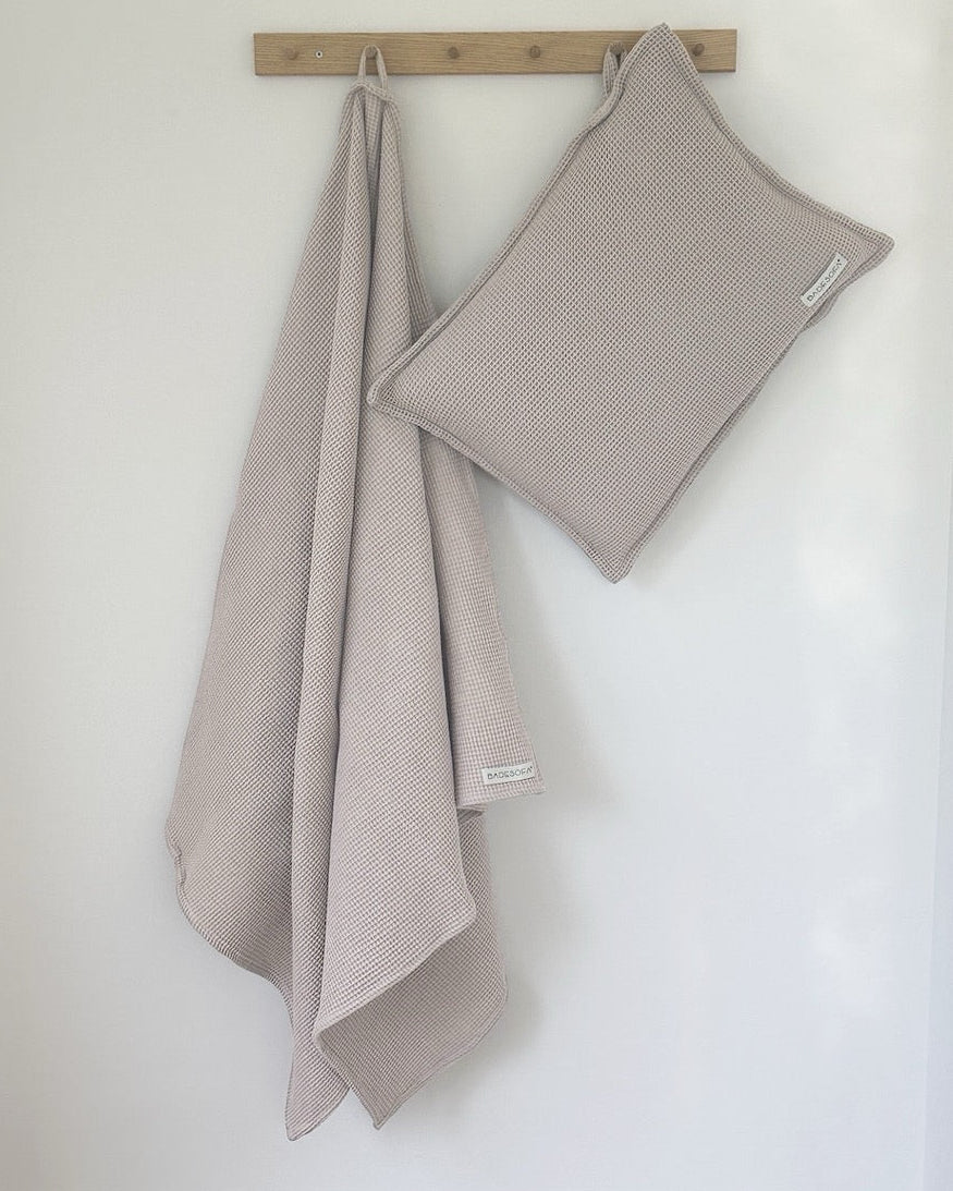 Kleiderhakenleiste aus Holz, an der ein Saunatuch und Saunasitzkissen hängen.