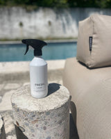 Reinigungsspray steht neben einem Poolsofa. 